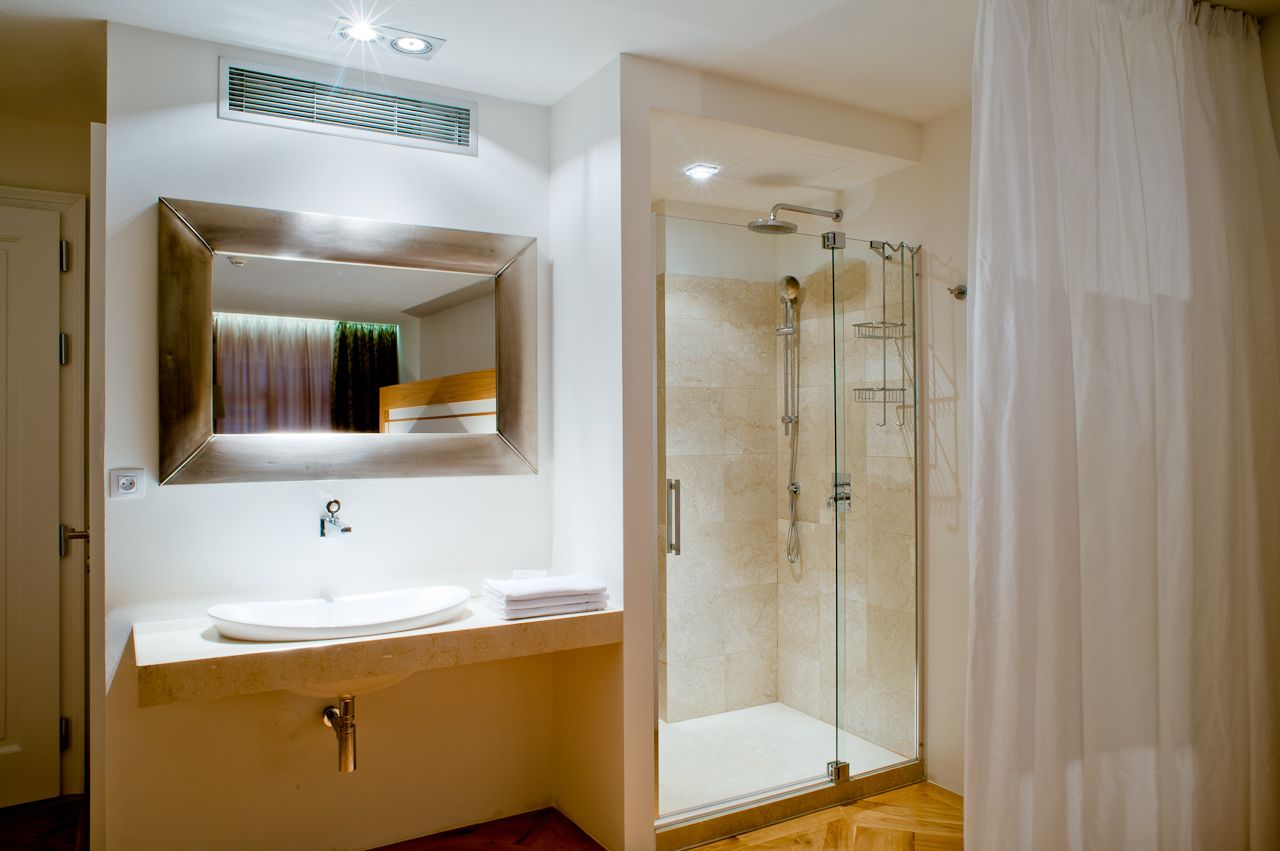 Uma casa de banho moderna com um espelho grande, uma pia e um chuveiro com parede de vidro.