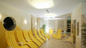 Un vestíbulo de hotel con sillones de color amarillo rayado, un espejo grande y una escalera que sube a un piso superior.