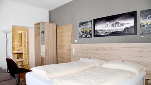 Una habitación de hotel con cama, escritorio, silla y armario.