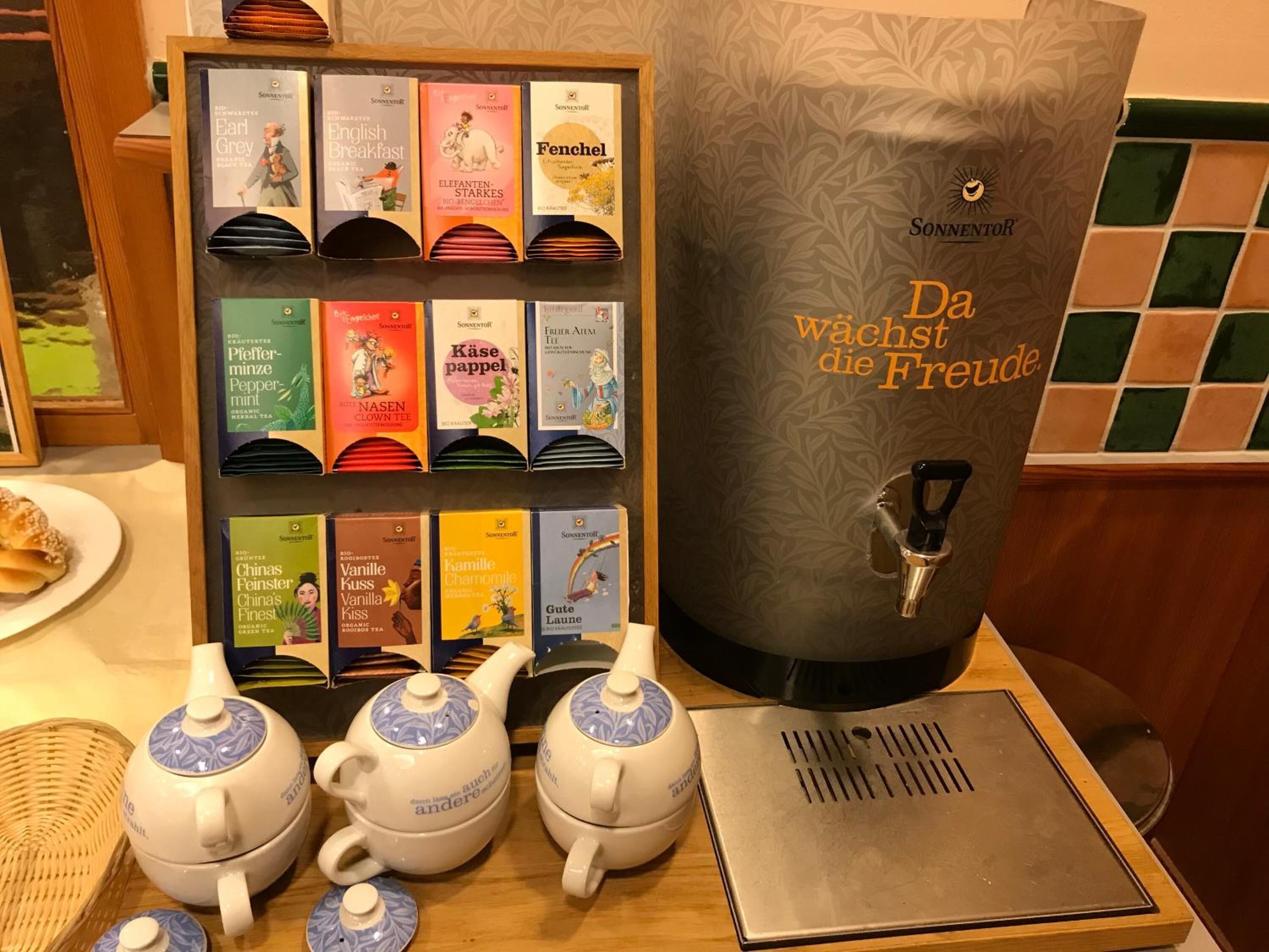 A tea station with a variety of tea boxes and two teapots on a wooden table.
