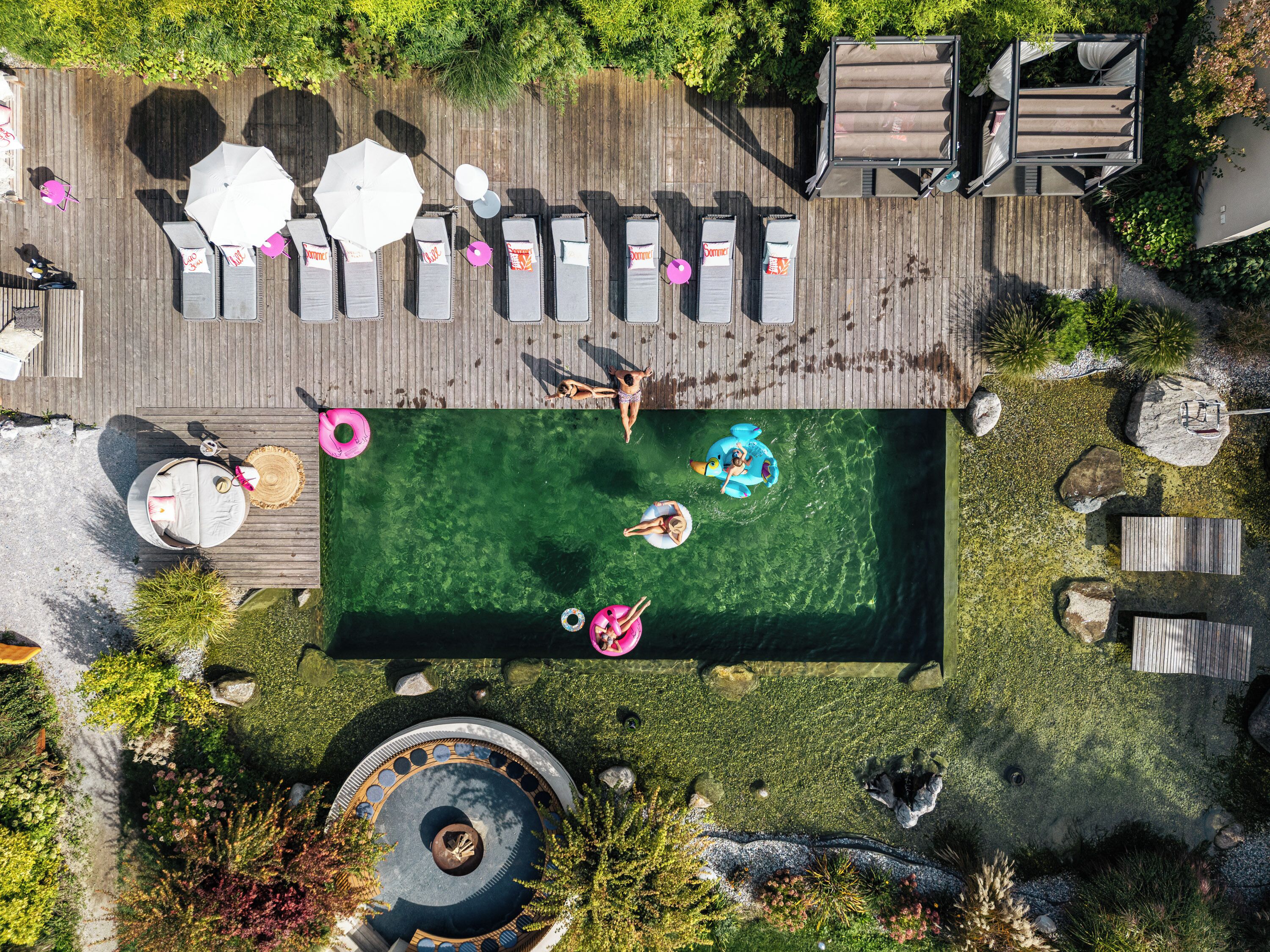 An aerial view of a pool area with lounge chairs, umbrellas, and a small inflatable pool.