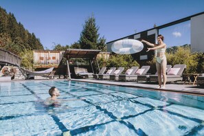 A swimming pool with lounge chairs and a covered area.