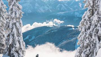 Un paysage de montagne enneigé, avec un randonneur au premier plan et une vue sur des montagnes et des vallées lointaines.