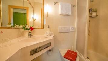 A bathroom with a sink, mirror, towel rack, toilet, and shower.