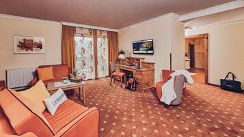 Une chambre d’hôtel équipée d’un canapé, d’un bureau, d’une télévision et d’une salle de bain visible à travers une porte ouverte.