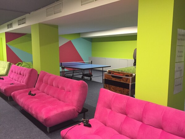 A room with bright green walls, a ping pong table, and two pink couches. - Sport- und Familienresort Alpenblick (Zell am See)