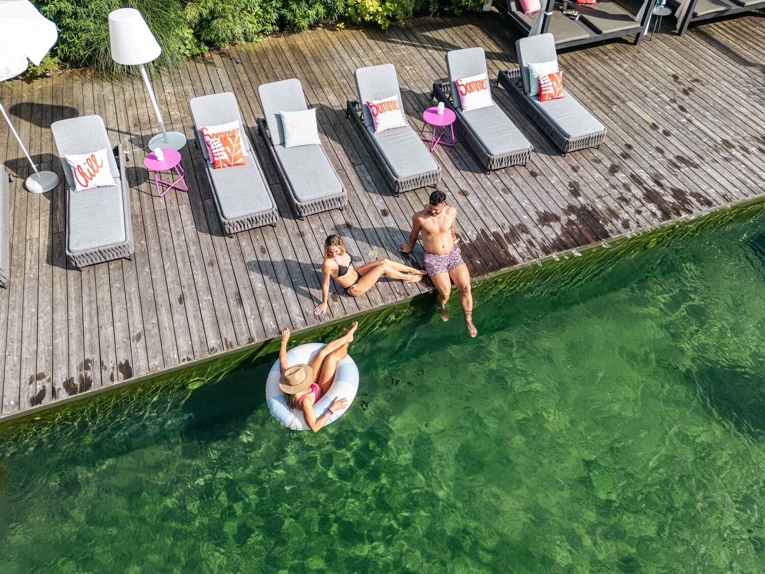 A wooden deck with lounge chairs and a pool.