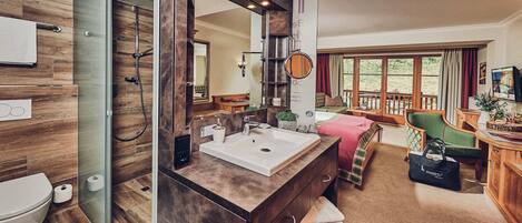 Un baño moderno con cabina de ducha de vidrio, un espejo grande y un mueble de tocador de madera.