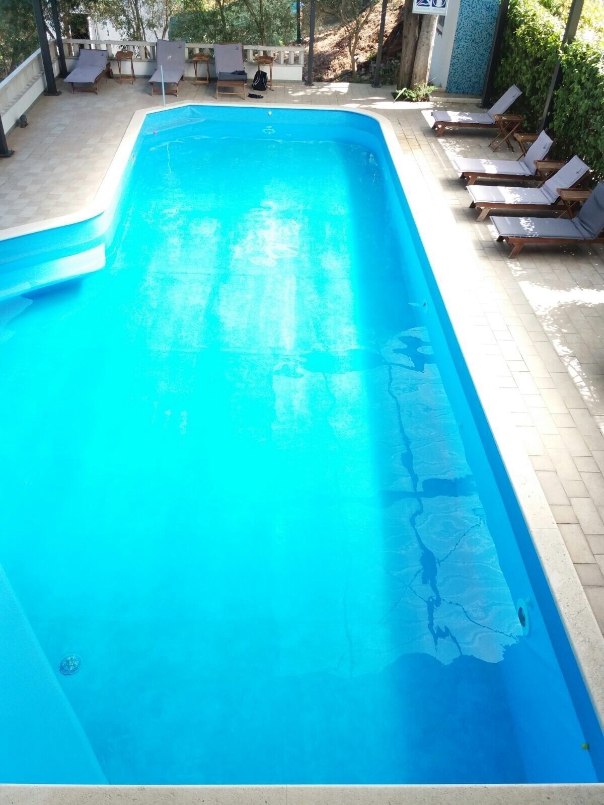 Una piscina al aire libre, sillones reclinables de piscina