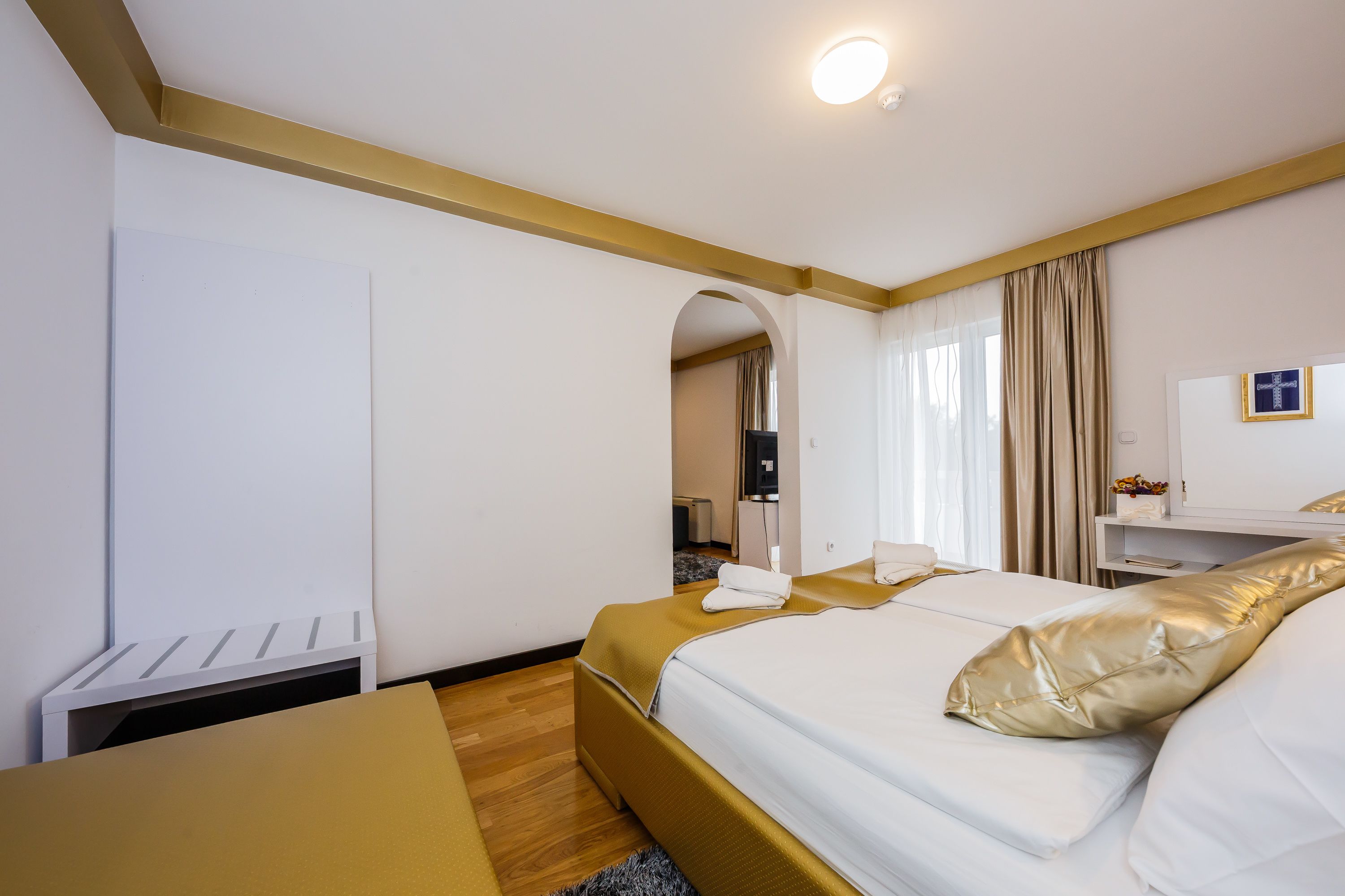A hotel room with a bed, a desk, a wardrobe, and a mirror.