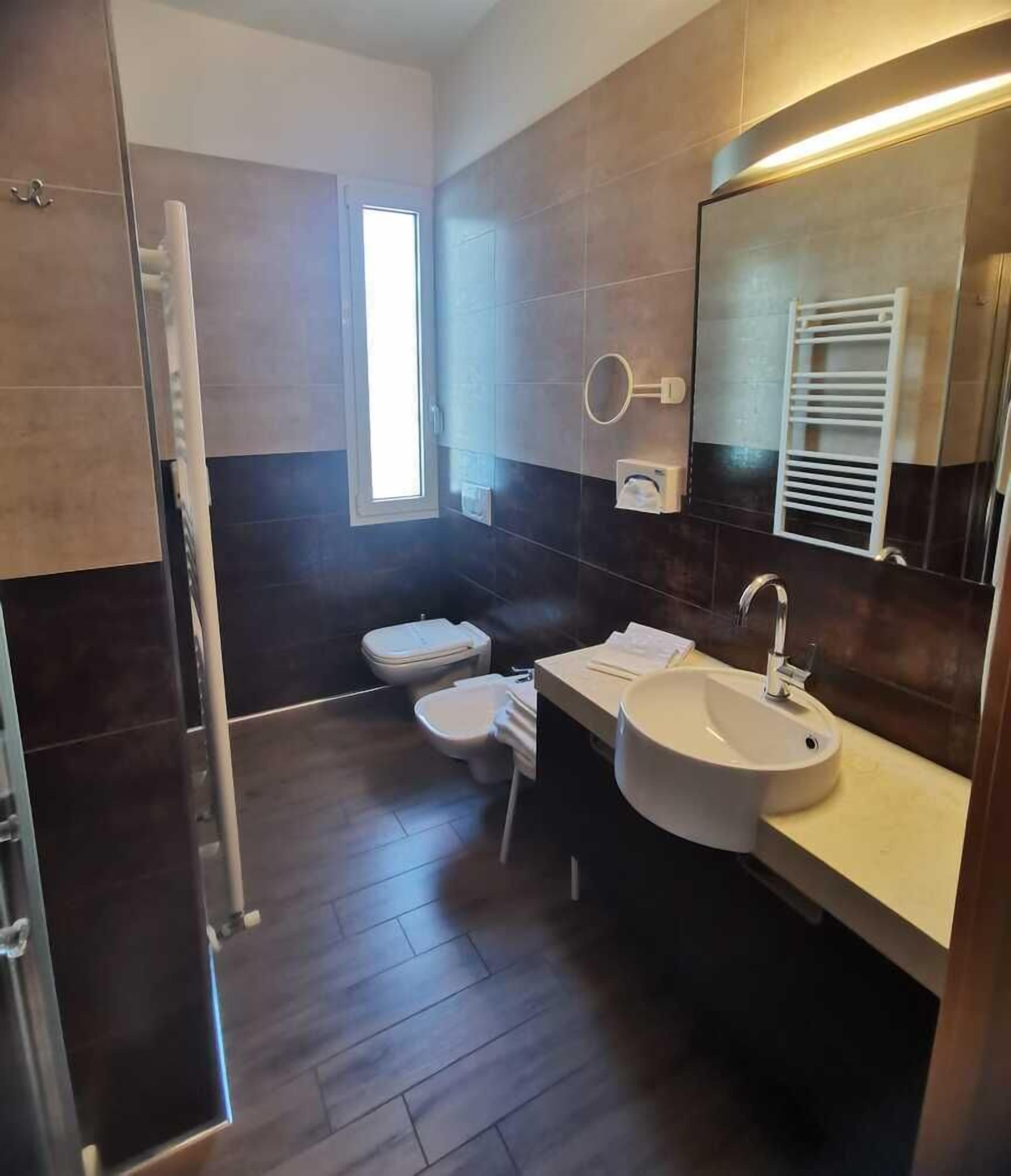 A modern bathroom with a large sink, a mirror, and two toilets.