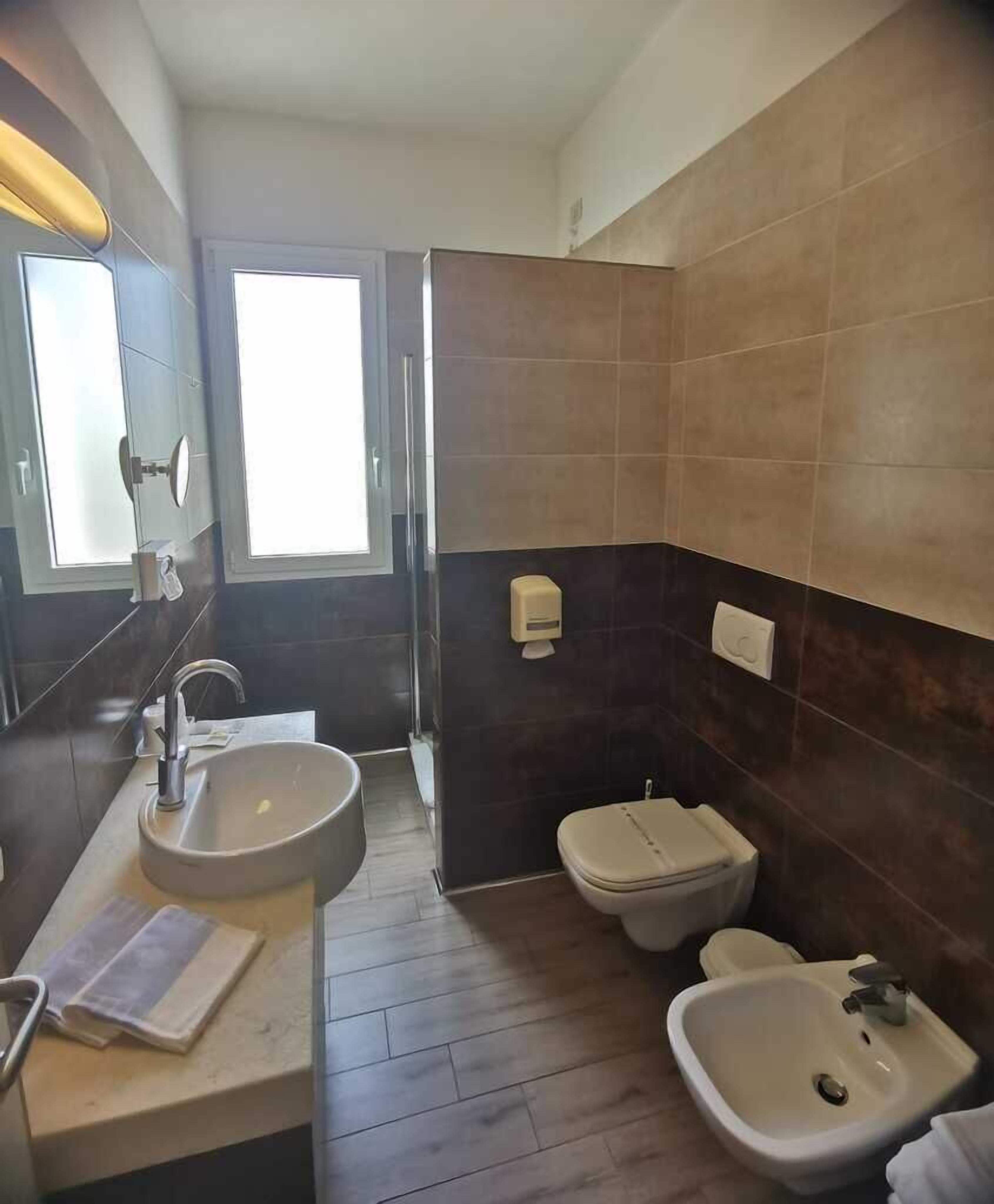 Ein modernes Badezimmer mit großem Spiegel, Waschbecken, Toilette und Bidet.