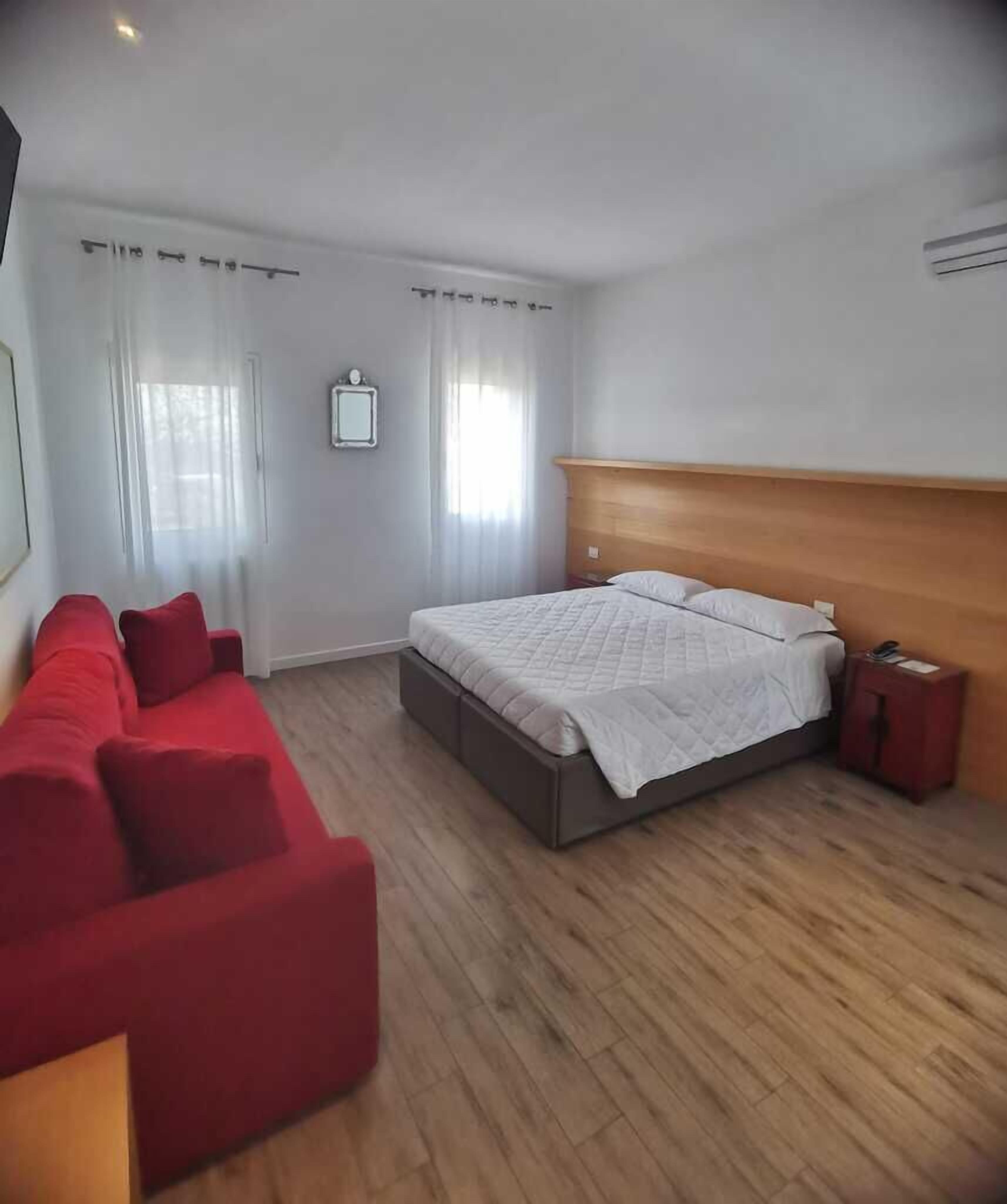 Un dormitorio con una cama, un sofá rojo y una mesita de noche.