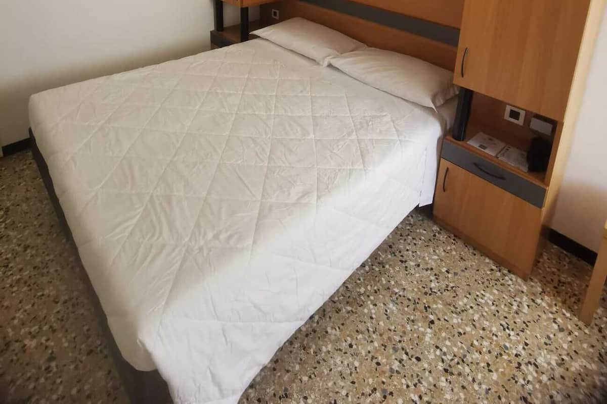 A bedroom with a bed, wooden headboard, and built-in storage cabinets.