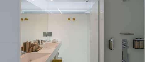 A modern bathroom with a large mirror, a sink with a towel rack, and a shower area with a handheld showerhead.