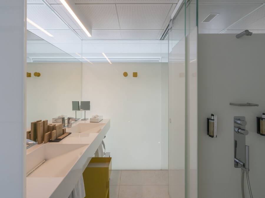 A modern bathroom with a large mirror, a sink with a towel rack, and a shower area with a handheld showerhead.