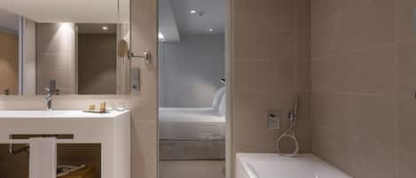 A modern bathroom with a large mirror, a bathtub, and a shower area.