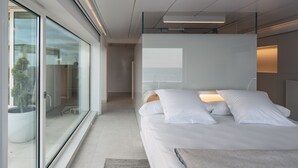 Un dormitorio moderno con una cama grande, una puerta de vidrio que da a un balcón y vistas al exterior.