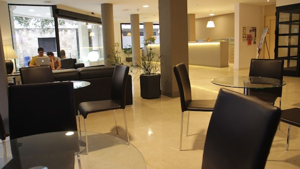 Una hall moderna con reception, area salotto con poltrone e divani, e un tavolino da caffè in vetro.