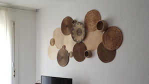 Un soggiorno moderno con un tavolo consolle bianco, un televisore a schermo piatto e un pannello decorativo intrecciato a parete.