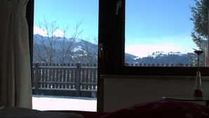 A room with a view of a snowy landscape, a wooden fence, and a table with a vase. - Haus Susanne (Radstadt)