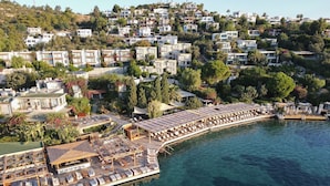 An aerial view of a coastal resort with a long, sunlit wooden deck with lounge chairs and a pool. - No 81 Hotel (Bodrum)
