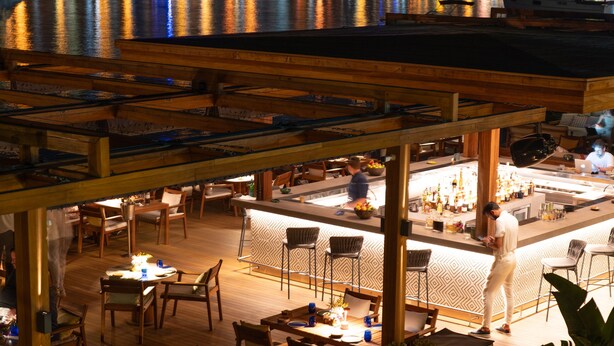 An outdoor dining area with wooden tables and chairs, a bar, and potted plants. - No 81 Hotel (Bodrum)