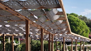 A poolside area with sun loungers aligned along the edge of a pool, wooden deck, and a canopy overhead. - No 81 Hotel (Bodrum)