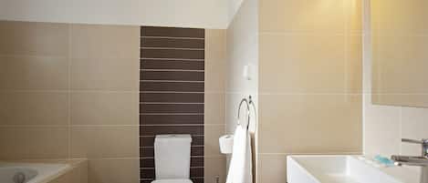 A bathroom with a bathtub, toilet, sink, and a mirror.