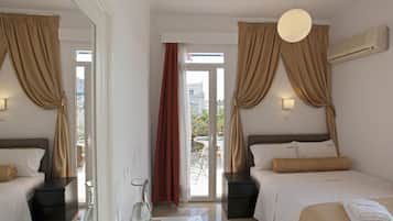 Een hotelkamer met twee bedden, een glazen bijzettafeltje, een nachtkastje met een lamp en uitzicht op het balkon.