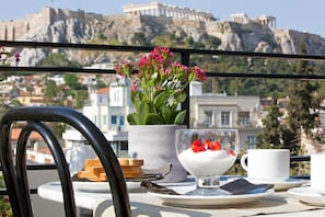 Una mesa con un postre, una taza y un arreglo floral, con vista a un edificio histórico al fondo.
