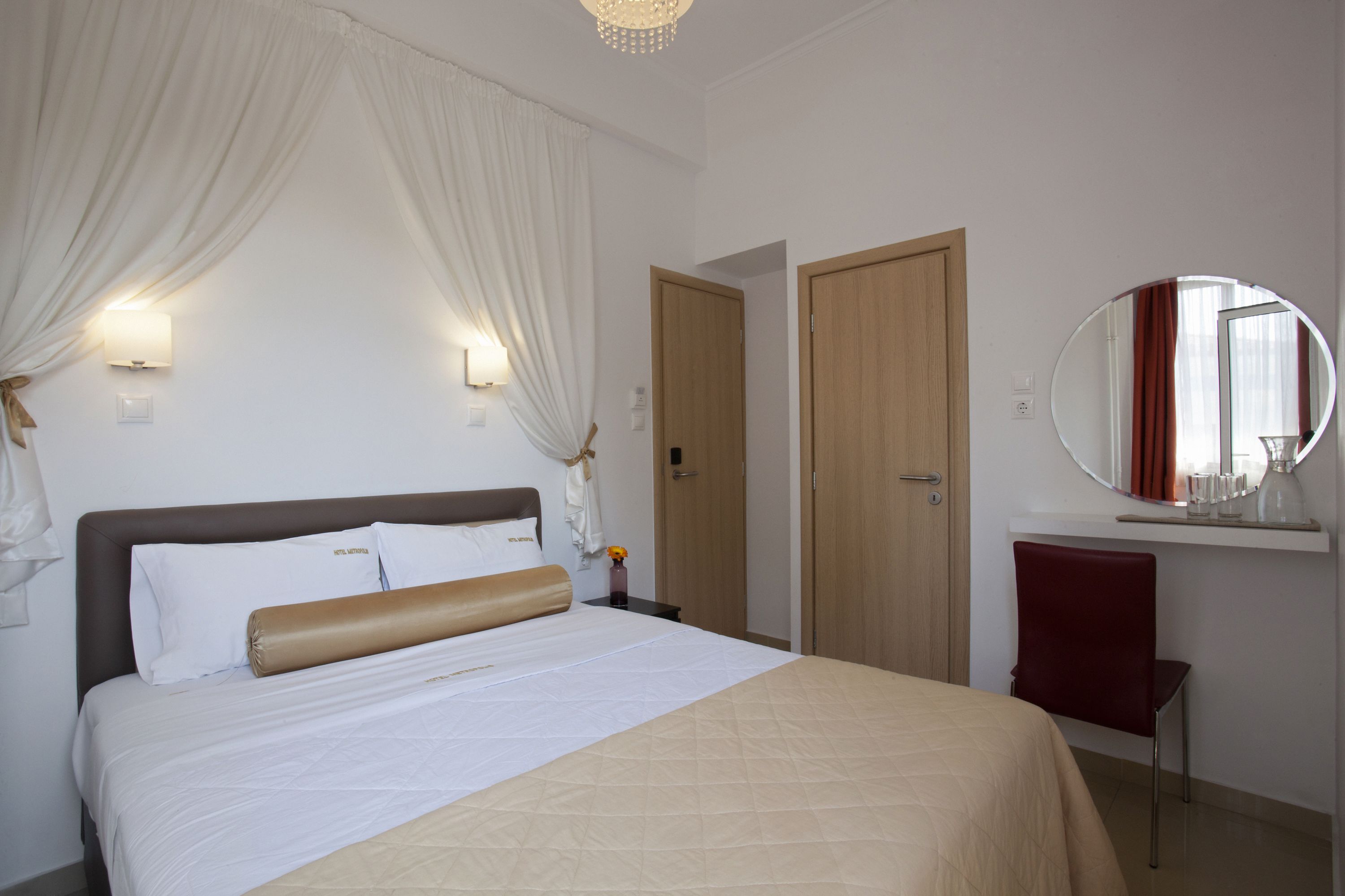 A hotel room with a bed, a mirror, a door, and a chair.