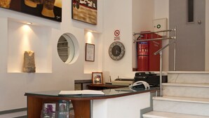 A reception desk with a computer, a fire extinguisher, and a clock on the wall. - Metropolis Hotel (Athens)