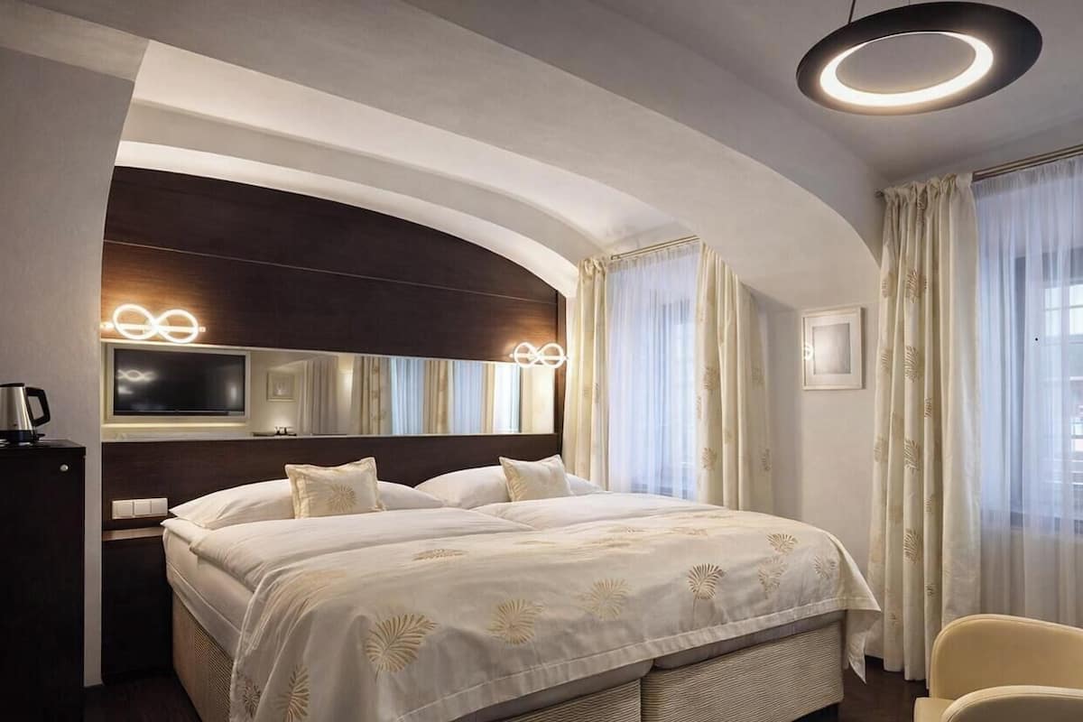 Habitación de hotel con una cama grande, televisor, escritorio con silla y una lámpara de techo circular.