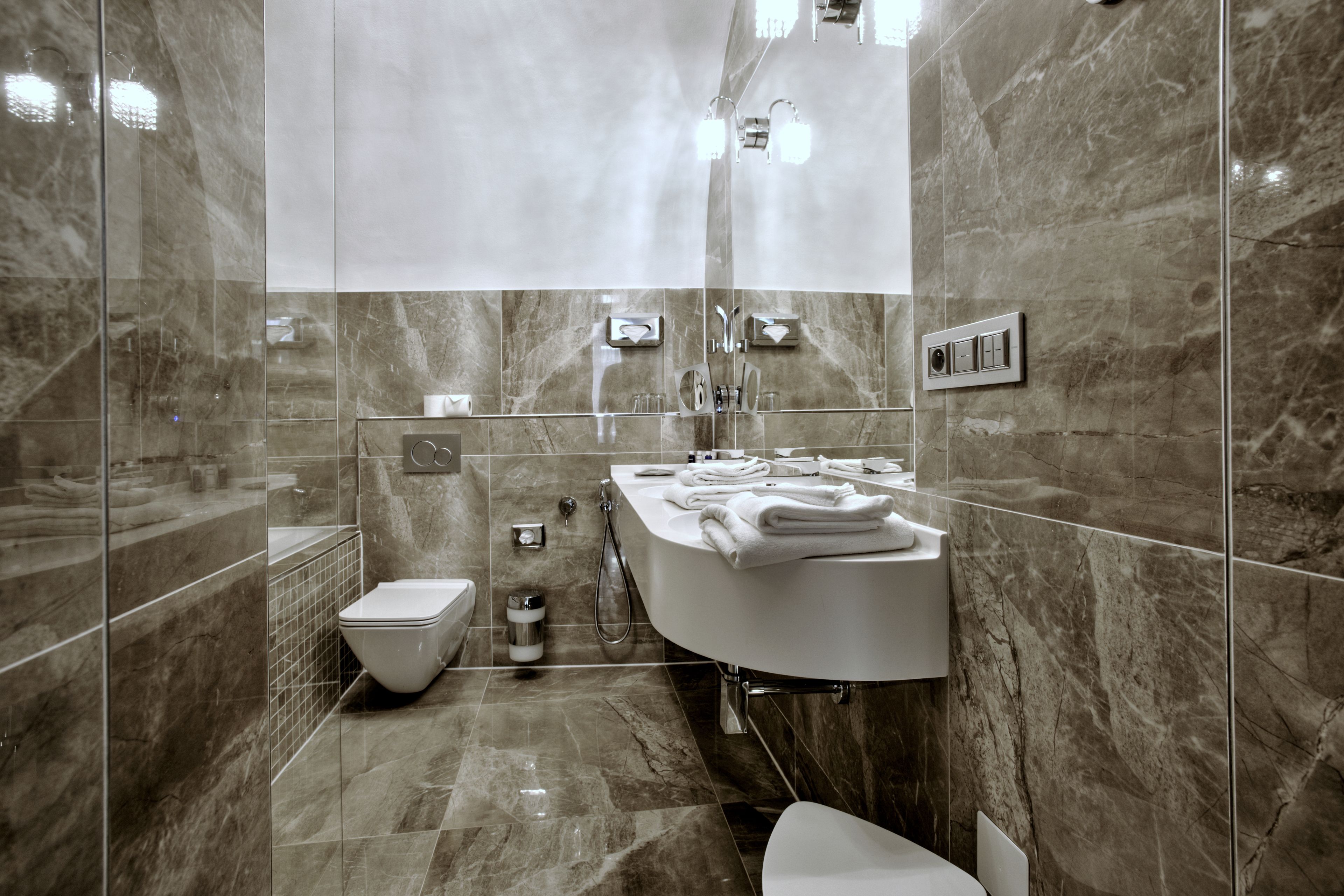 Une salle de bain moderne avec une douche à parois de verre, des toilettes blanches et une grande baignoire agrémentée de serviettes soigneusement pliées.