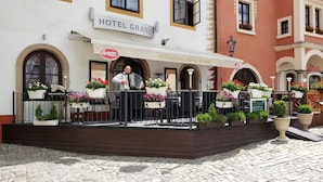 Un hôtel doté d’une terrasse de restaurant, de sièges en plein air et de plantes en pot.