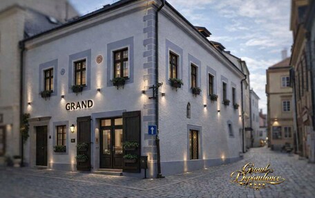 A building with the sign 'GRAND Dependance' on the facade, featuring multiple windows and a cobblestone street.