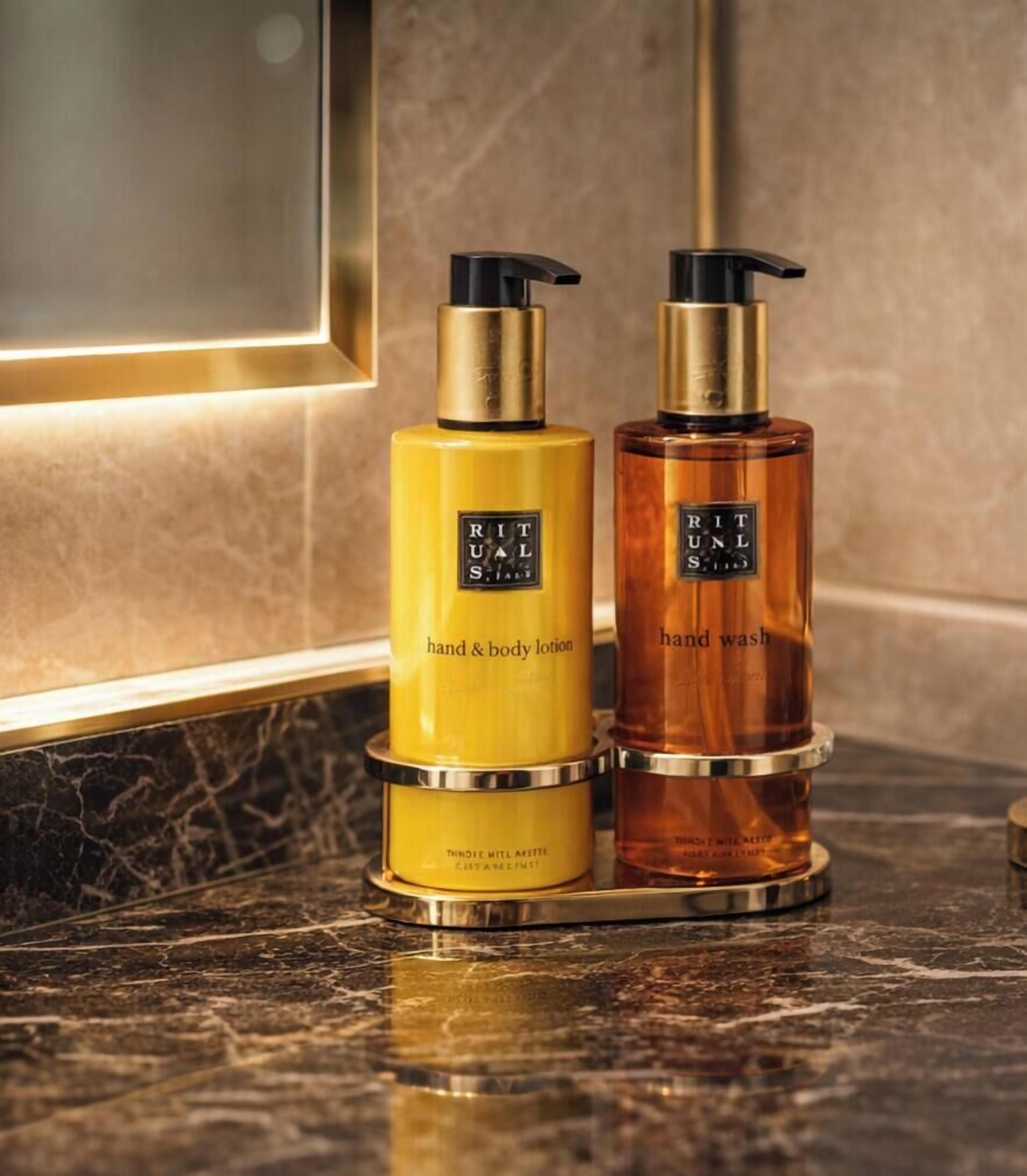 Two bottles of hand and body lotion and hand wash on a marble countertop.