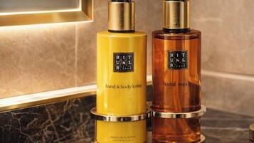 Two bottles of hand and body lotion and hand wash on a marble countertop.