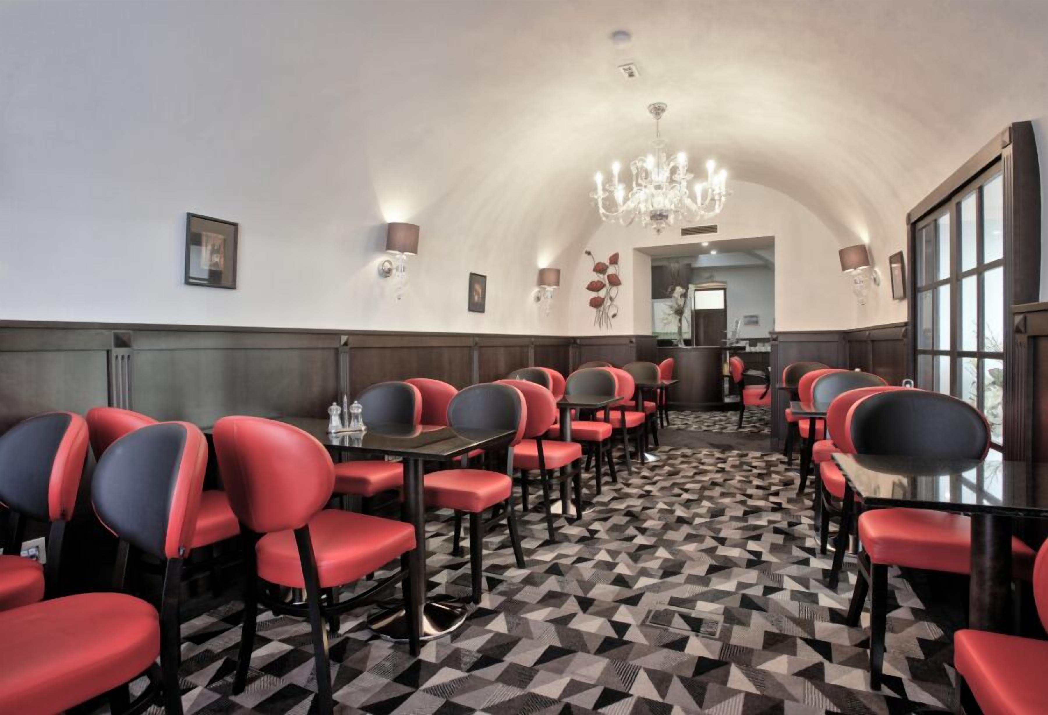 A conference room with red and black chairs, a patterned floor, and a chandelier.