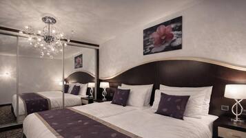 A hotel room with a large bed, a chandelier, a mirror, and a flower painting on the wall.