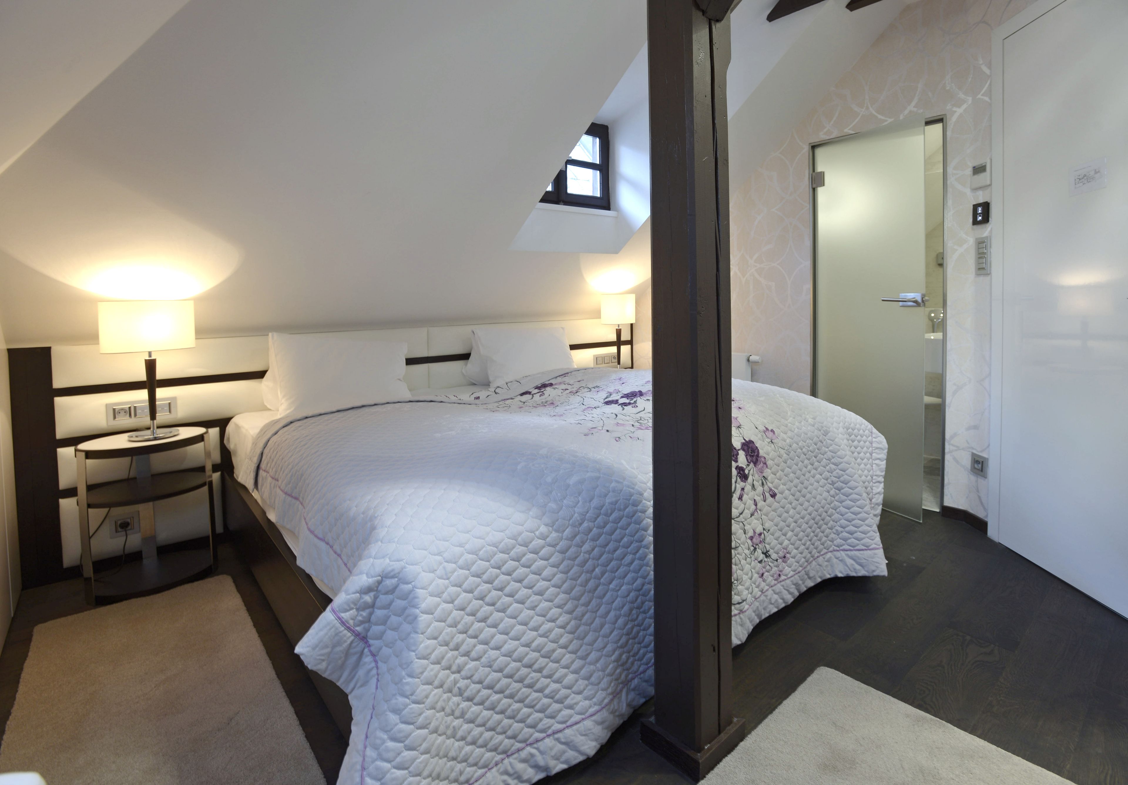 A bedroom with a bed, bedside tables, a nightstand, a window, and a door.