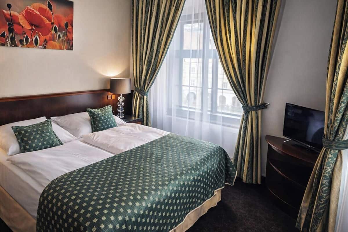 Una habitación de hotel con una cama grande, televisión y cortinas.
