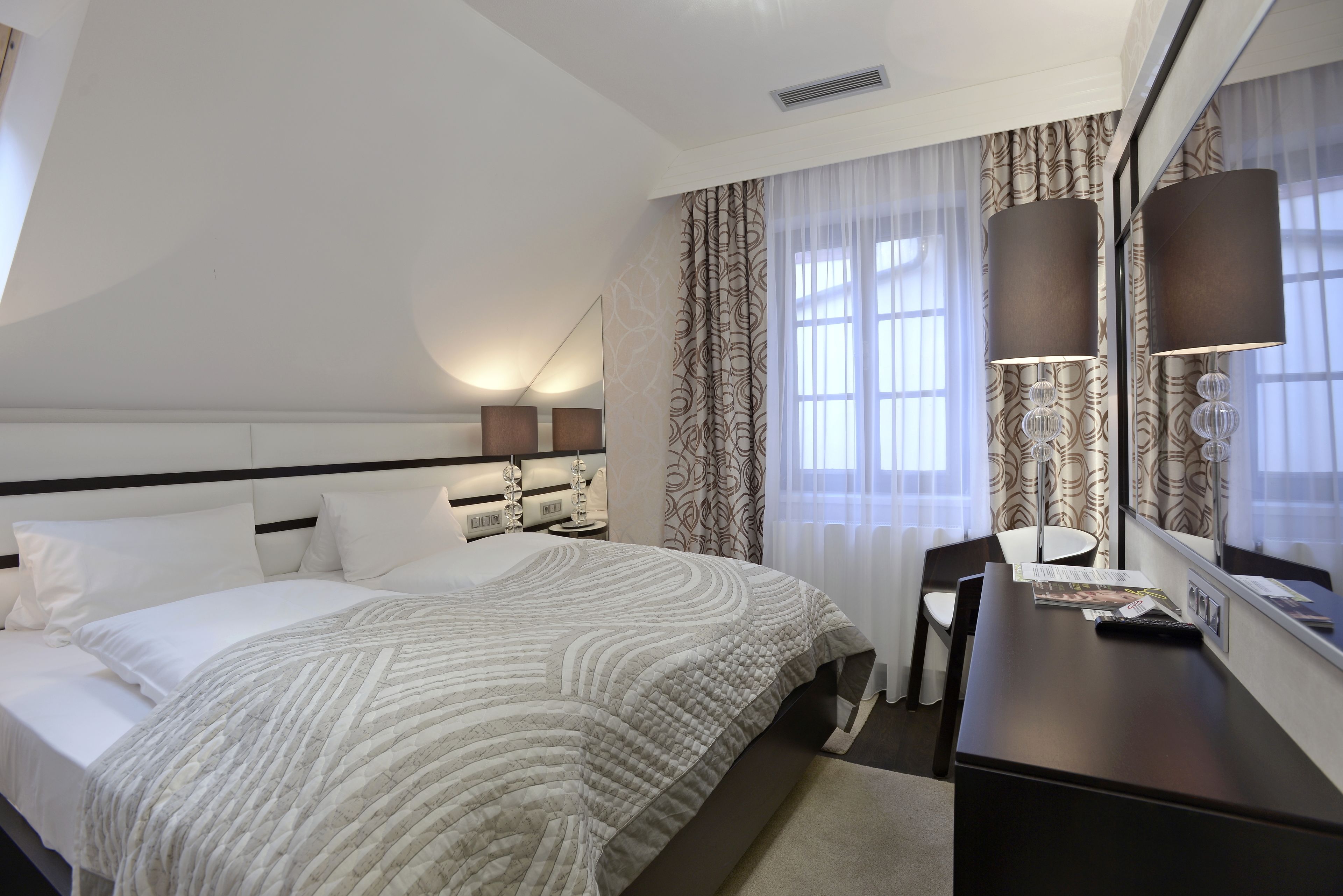 Habitación de hotel con una cama grande, un escritorio, una silla y un espejo.