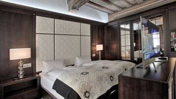 A modern hotel room with a large bed, a bedside table with a lamp, a dresser, and a large mirror.
