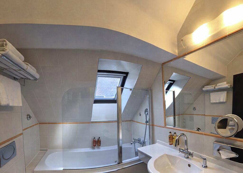 A modern bathroom with a bathtub, shower, and sink.
