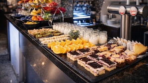 Un buffet proposant une variété de fruits, de desserts et de milkshakes.