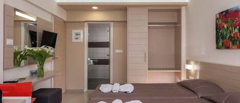 A modern hotel room with a bed, a desk, a chair, a TV, a bathroom, and a closet.