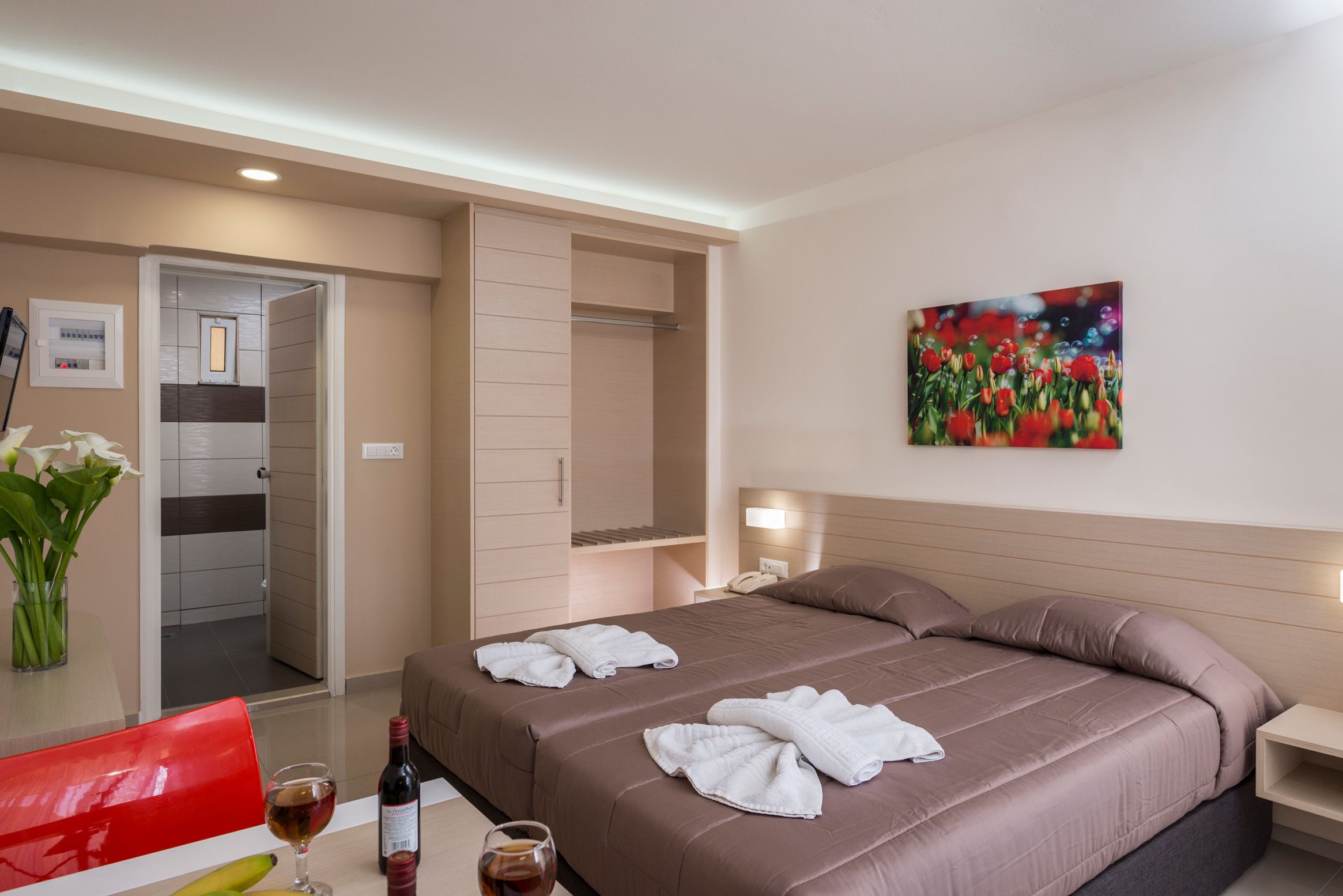 A hotel room with a bed, bedside table, and a painting on the wall.