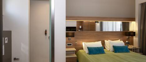 Une chambre d’hôtel moderne avec un grand lit, des tables de chevet, un miroir et un espace douche.